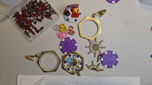 Craft table covered with poker chips, chip ducks, and ship wheel charms mid-creation