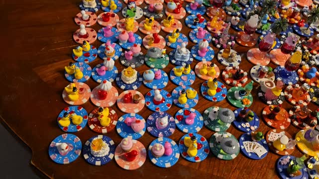 A whole table covered with dozens of finished decorated poker chip ducks